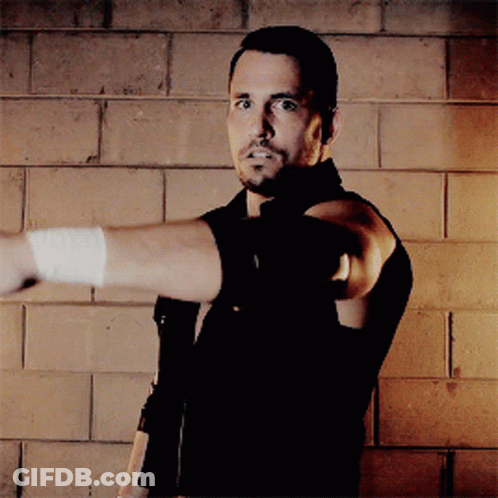 A Man With A Bandage On His Arm Is Pointing At Something GIF