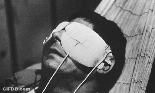 A Man With A Bandage On His Eye Is Laying On A Bed GIF