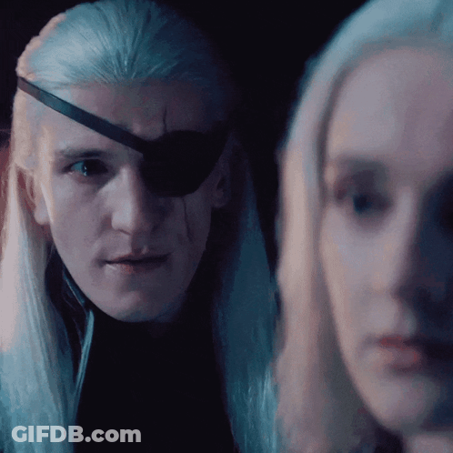 A Man With A Bandage On His Eye Looks At A Woman In A Dark Room GIF