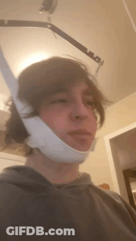 A Man With A Bandage On His Face Is Standing In A Room GIF
