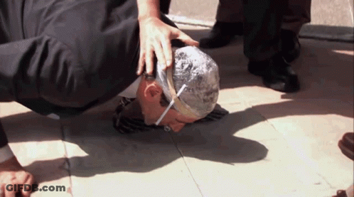 A Man With A Bandage On His Head Is Kneeling Down On The Ground GIF