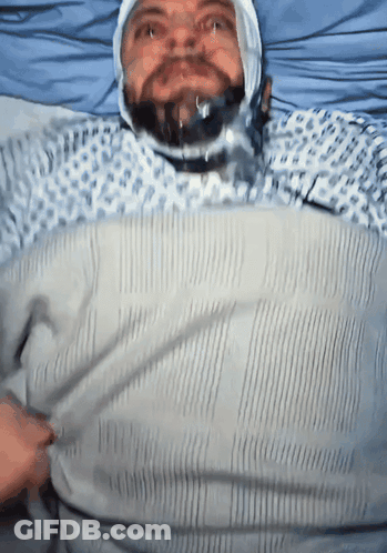 A Man With A Bandage On His Head Is Laying In Bed GIF