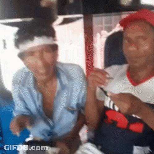 A Man With A Bandage On His Head Is Sitting Next To Another Man Wearing A Red Hat GIF