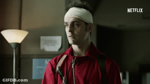 A Man With A Bandage On His Head Is Standing In Front Of A Sign That Says Netflix On It GIF