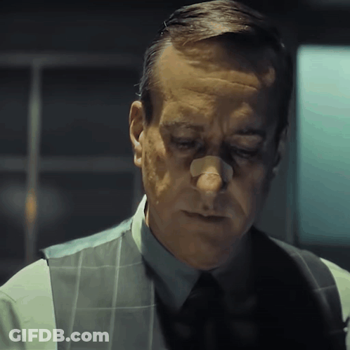 A Man With A Bandage On His Nose Is Wearing A Vest And Tie GIF