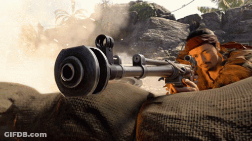 A Man With A Bandana Around His Head Is Holding A Rifle GIF