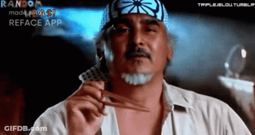 A Man With A Bandana On His Head Is Holding A Pair Of Scissors And A Card . GIF