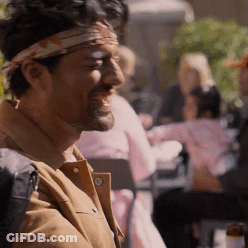 A Man With A Bandana On His Head Is Laughing At Something GIF