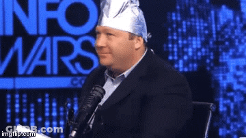 A Man With A Bandana On His Head Is Sitting In Front Of A Microphone With The Words Info Wars Behind Him GIF