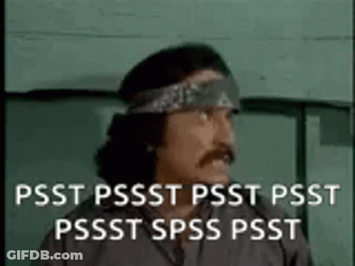 A Man With A Bandana On His Head Is Standing In Front Of A Green Wall . GIF