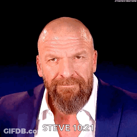 A Man With A Beard And A Bald Head Is Wearing A Blue Suit And A White Shirt . GIF