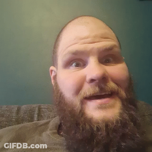 A Man With A Beard And A Bald Head Looks Down At The Camera GIF