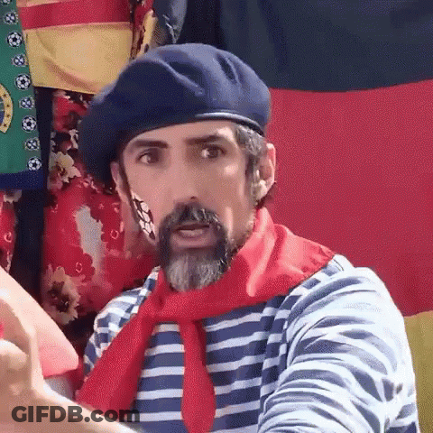 A Man With A Beard And A Beret Is Wearing A Striped Shirt And A Red Scarf . GIF