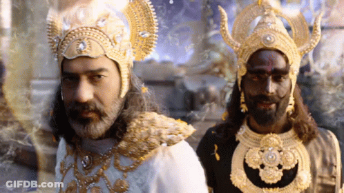 A Man With A Beard And A Black Face Is Standing Next To Another Man In A Costume GIF