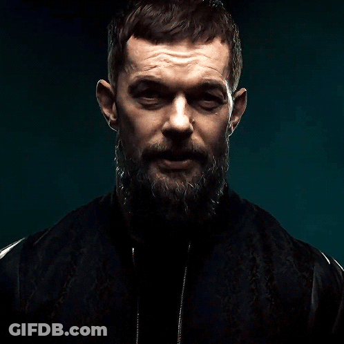 A Man With A Beard And A Black Jacket Is Looking At The Camera GIF