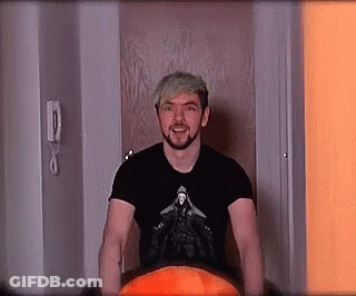 A Man With A Beard And A Black Shirt Is Standing In A Doorway . GIF