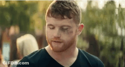 A Man With A Beard And A Black Shirt Is Standing In Front Of A Crowd . GIF