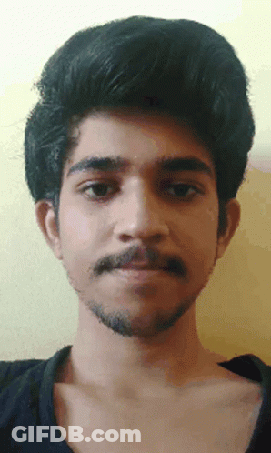 A Man With A Beard And A Black Shirt Looks At The Camera GIF