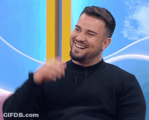 A Man With A Beard And A Black Sweater Is Smiling GIF