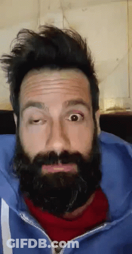 A Man With A Beard And A Blue Jacket Is Making A Funny Face GIF