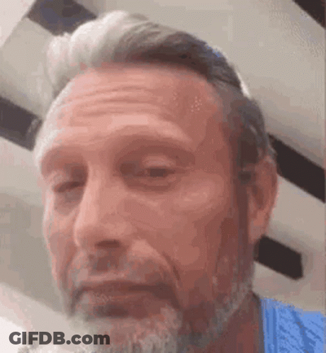 A Man With A Beard And A Blue Shirt Is Making A Face . GIF