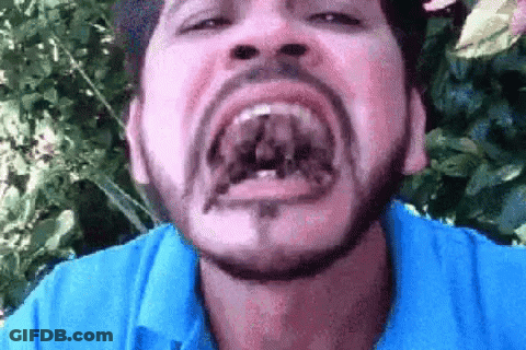 A Man With A Beard And A Blue Shirt Is Making A Funny Face . GIF