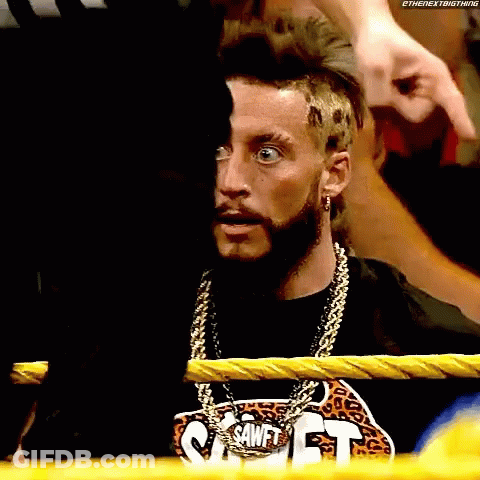 A Man With A Beard And A Chain Around His Neck Is Sitting In A Boxing Ring . GIF