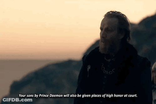 A Man With A Beard And A Chain Around His Neck Is Standing On Top Of A Hill . GIF