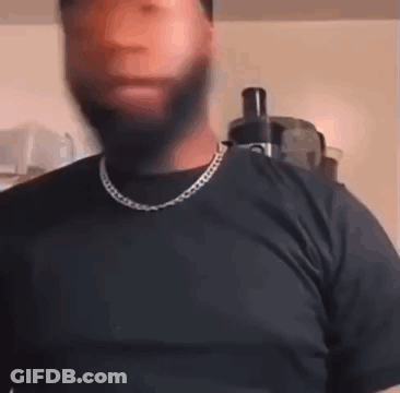 A Man With A Beard And A Chain Around His Neck Is Wearing A Black Shirt And A Black T-Shirt . GIF