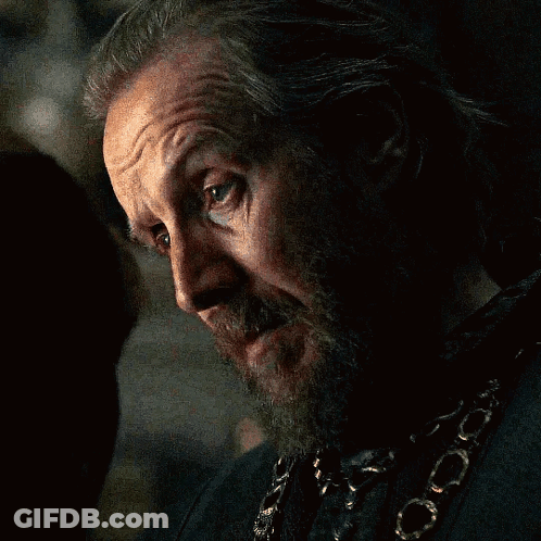 A Man With A Beard And A Chain Around His Neck Looks At The Camera GIF