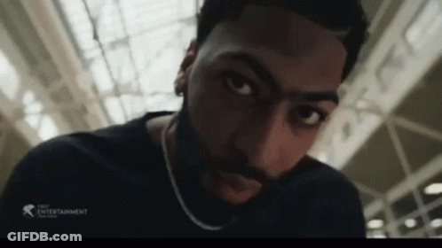 A Man With A Beard And A Chain Around His Neck Looks At The Camera GIF