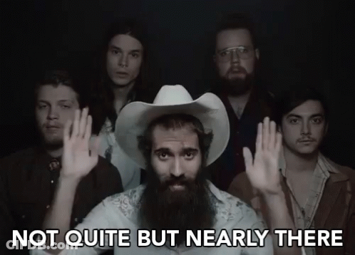 A Man With A Beard And A Cowboy Hat Says Not Quite But Nearly There In Front Of A Group Of Men GIF
