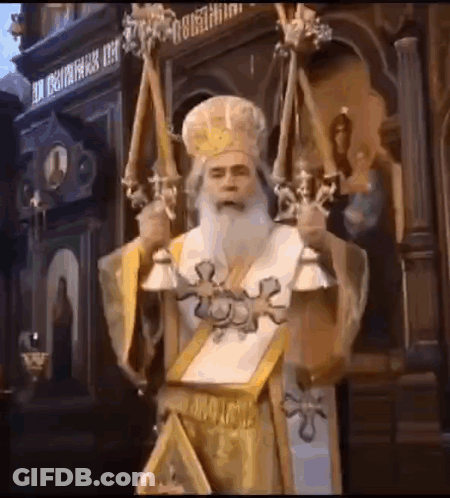 A Man With A Beard And A Crown Is Holding Candles And A Book In A Church . GIF