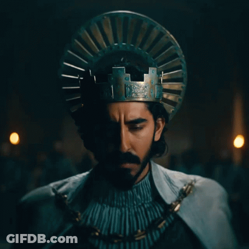 A Man With A Beard And A Crown On His Head Looks At The Camera GIF