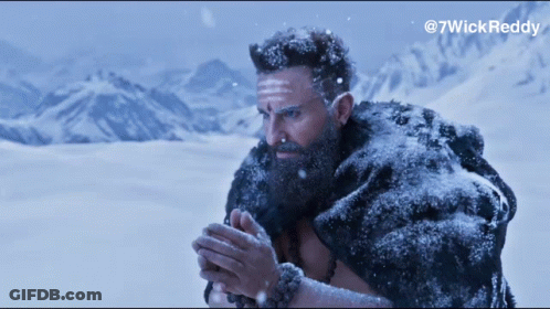 A Man With A Beard And A Fur Coat Is Standing In The Snow With Mountains In The Background GIF