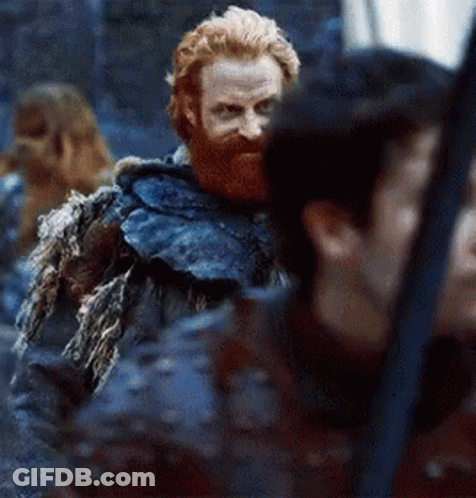 A Man With A Beard And A Fur Coat Is Standing Next To A Woman . GIF