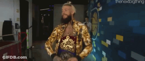 A Man With A Beard And A Gold Jacket Is Standing In Front Of A Wall . GIF