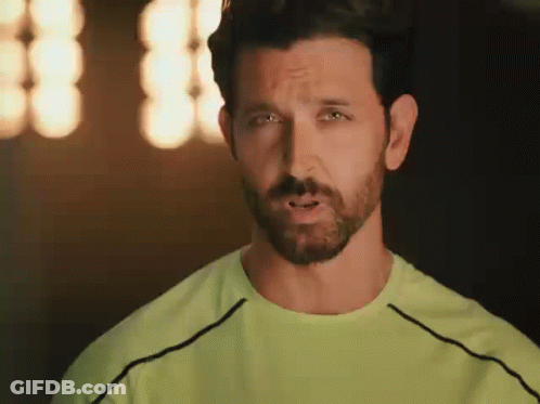 A Man With A Beard And A Green Shirt Is Making A Face . GIF