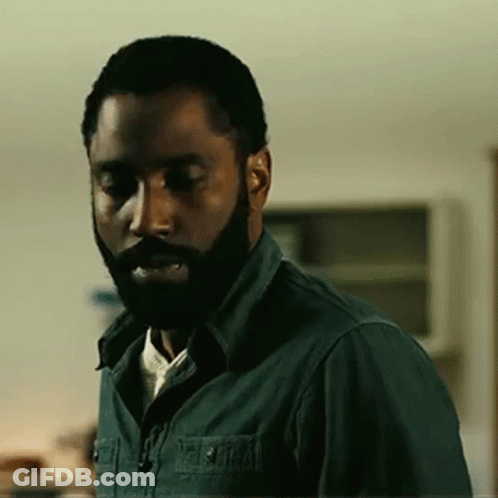 A Man With A Beard And A Green Shirt Is Standing In A Room . GIF
