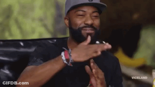 A Man With A Beard And A Hat Is Clapping His Hands . GIF