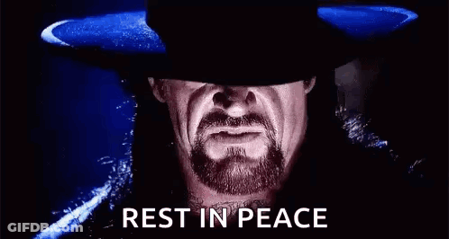 A Man With A Beard And A Hat Is Standing In The Dark . GIF
