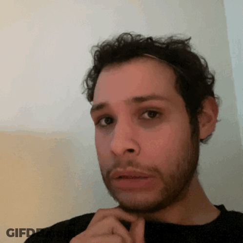 A Man With A Beard And A Headband On His Head Looks At The Camera GIF