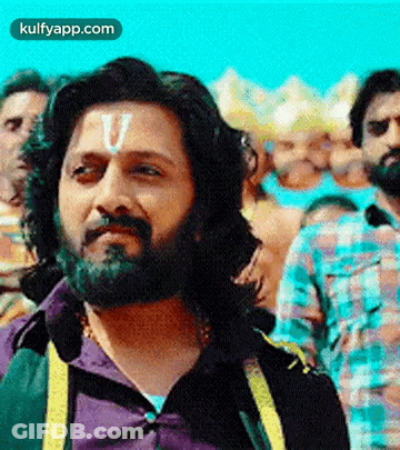 A Man With A Beard And A Letter U On His Forehead Is Standing In A Crowd Of People . GIF