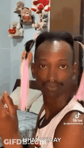 A Man With A Beard And A Nose Ring Is Sitting In A Bedroom . GIF