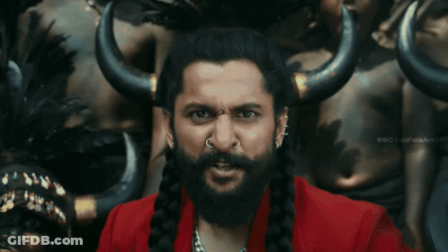 A Man With A Beard And A Nose Ring Is Standing In Front Of A Group Of People With Horns GIF