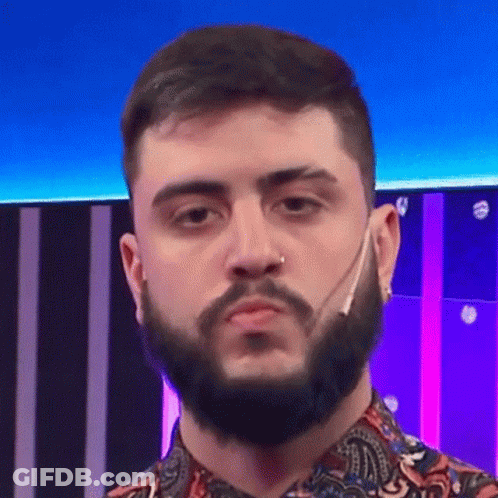 A Man With A Beard And A Nose Ring Is Wearing A Paisley Shirt And Making A Funny Face . GIF