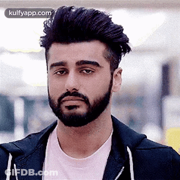 A Man With A Beard And A Pink Shirt Is Wearing A Black Jacket And A Pink Shirt . GIF