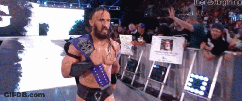 A Man With A Beard And A Purple Belt Stands In Front Of A Crowd Of People . GIF