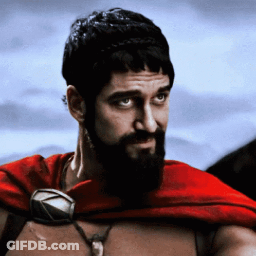 A Man With A Beard And A Red Cape Looks At The Camera GIF