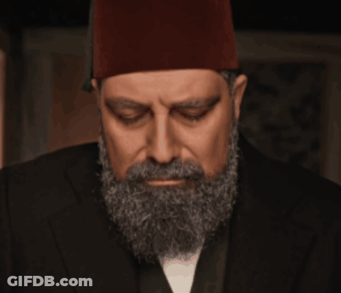 A Man With A Beard And A Red Hat Looks Down GIF